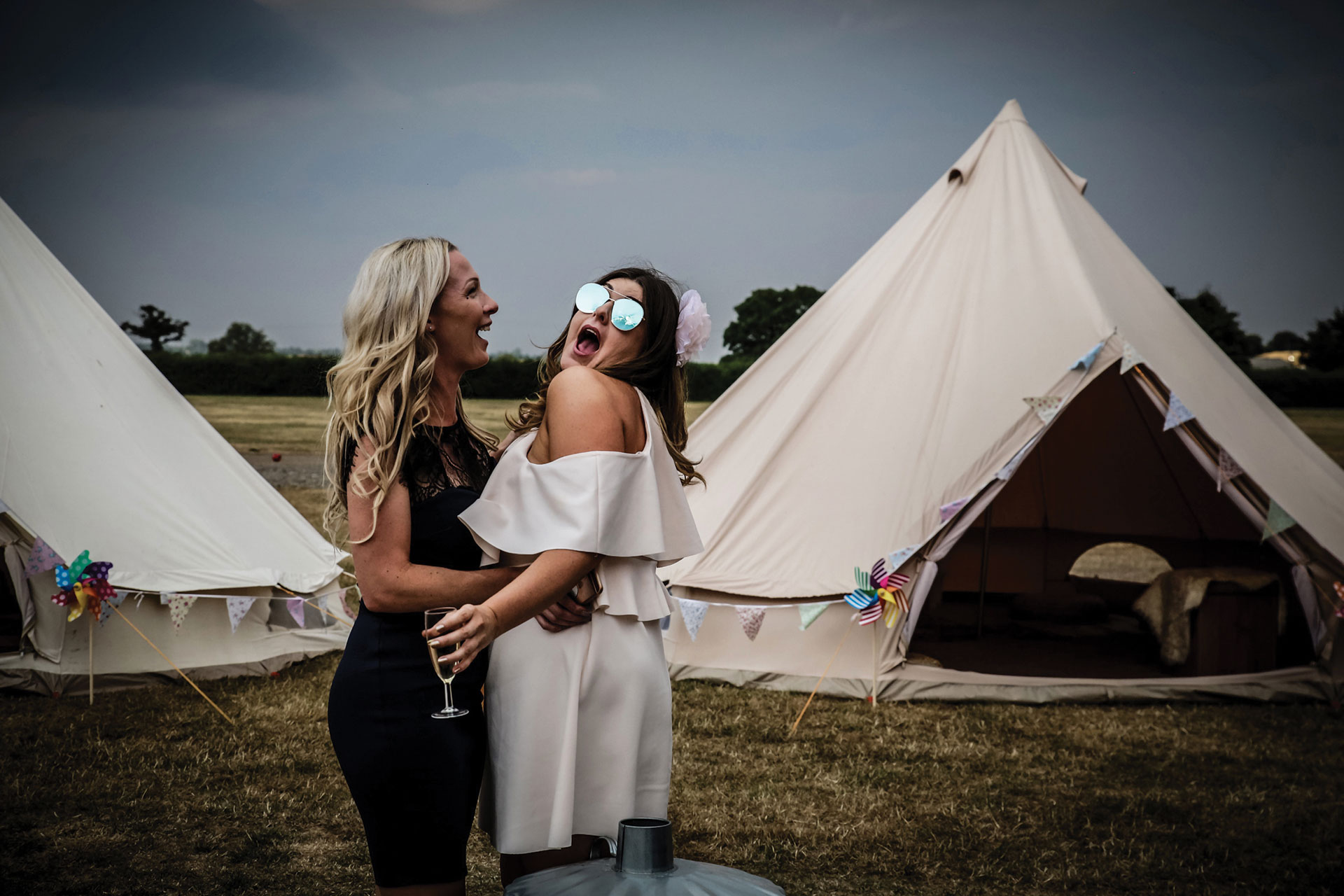Two women having fun and smiling near tents