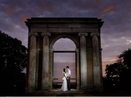 couple on wedding day under an arch in the evening at Tendring Hall Estate