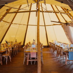 Single tipi set for a dinner party on rustic rectangle tables