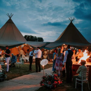 Double tipi at night with a fire pit for cooler nights celebration