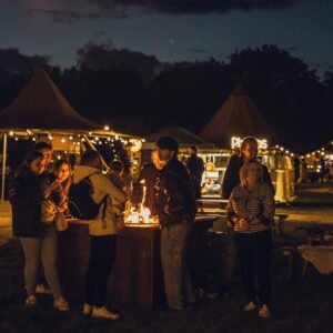 Tipi set up for a corporate winter party with people standing around a fire pit